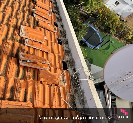 רעפים כתומים על גג עם צלחת לוויין וחוטים